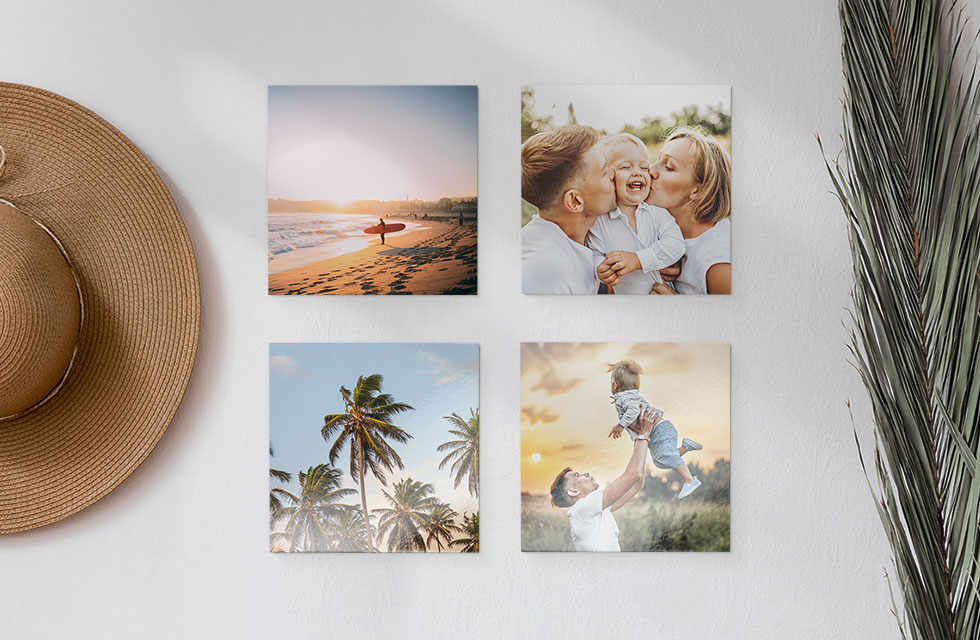 A set of four Snapfish Photo Tiles featuring family and vacation photos is displayed on a wall with a hat and plant nearby