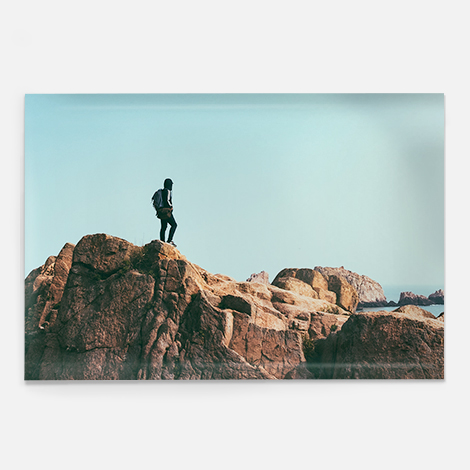 Single photo poster showing a lone man standing on top of rocky landscape. 